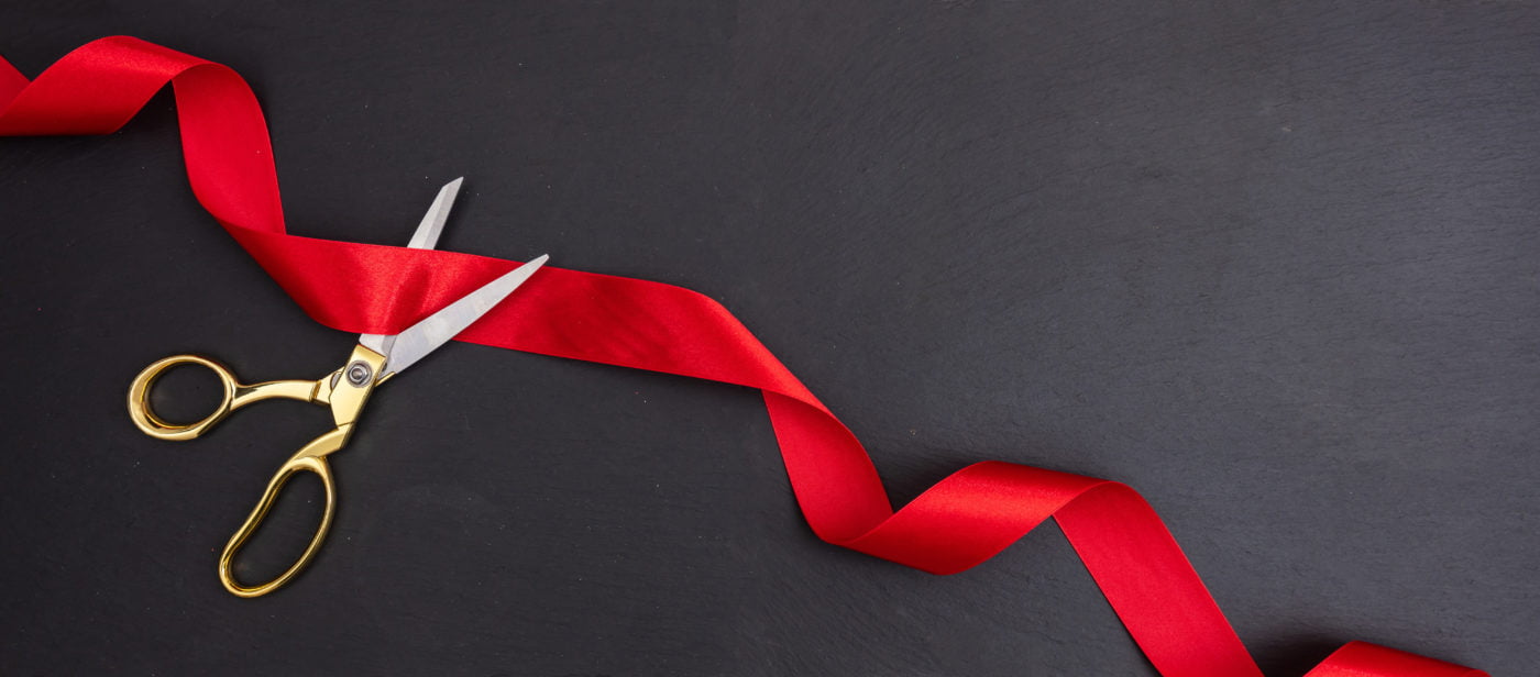 Scissors cutting red ribbon banner