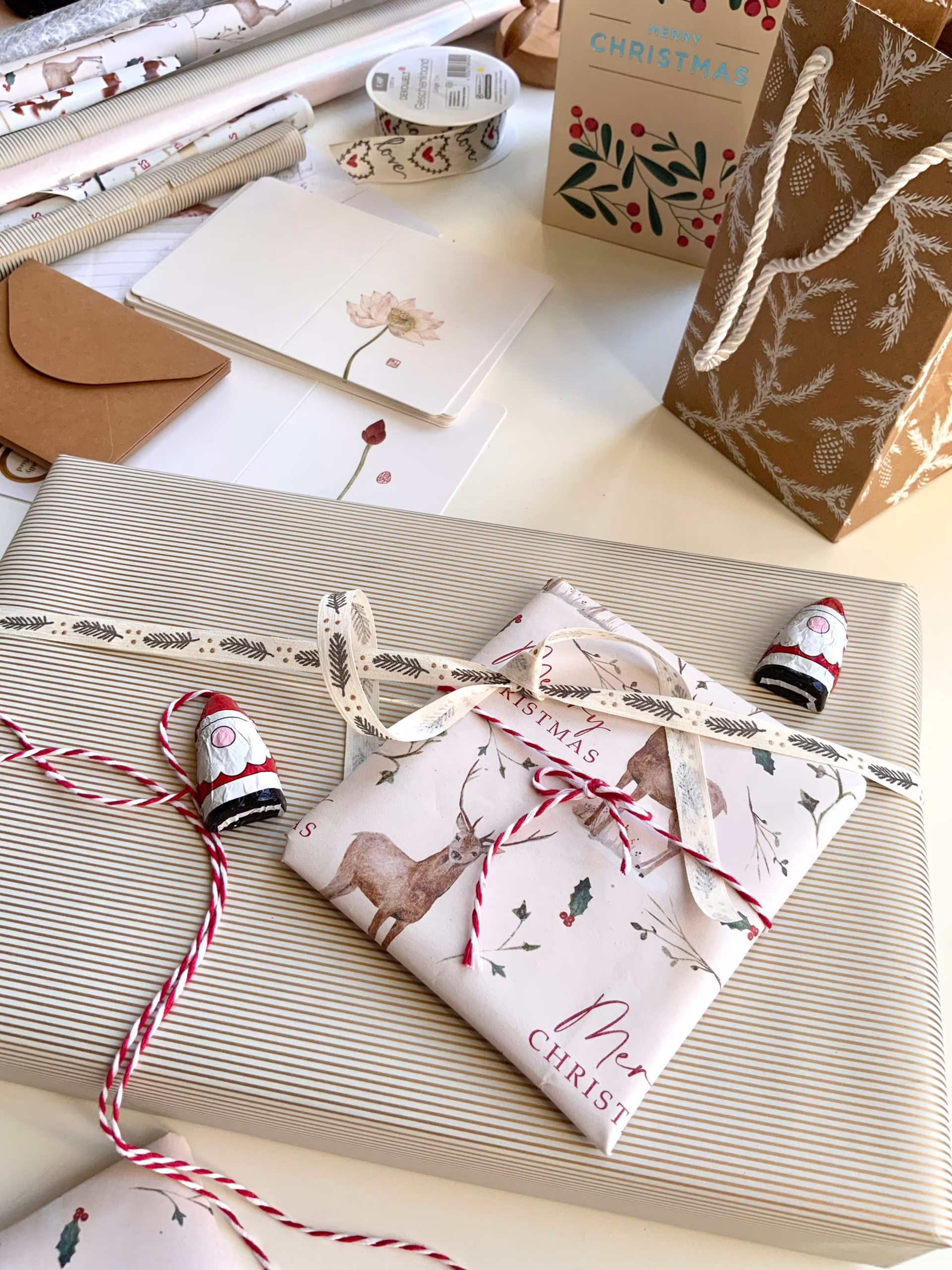 pexels-iris-35308744 - The Ribbon Company Holiday gift-w wrapping setup with striped and patterned paper, ribbon, and a small wrapped present featuring a botanical card.